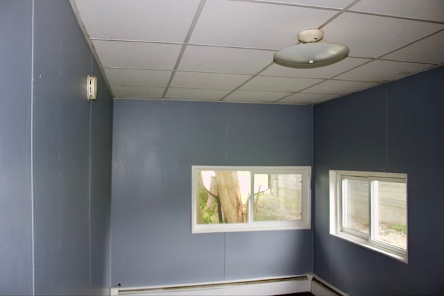 spare room with baseboard heating and a drop ceiling