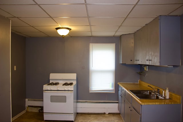 kitchen with a drop ceiling, sink, a baseboard radiator, light tile patterned flooring, and white range with gas cooktop