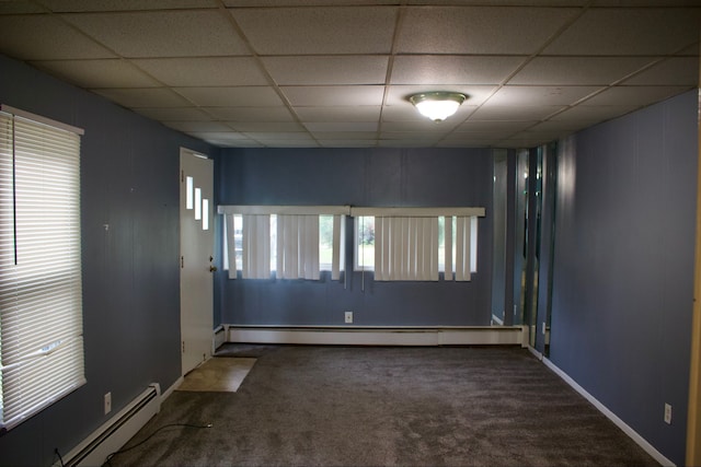 carpeted empty room featuring a paneled ceiling and baseboard heating