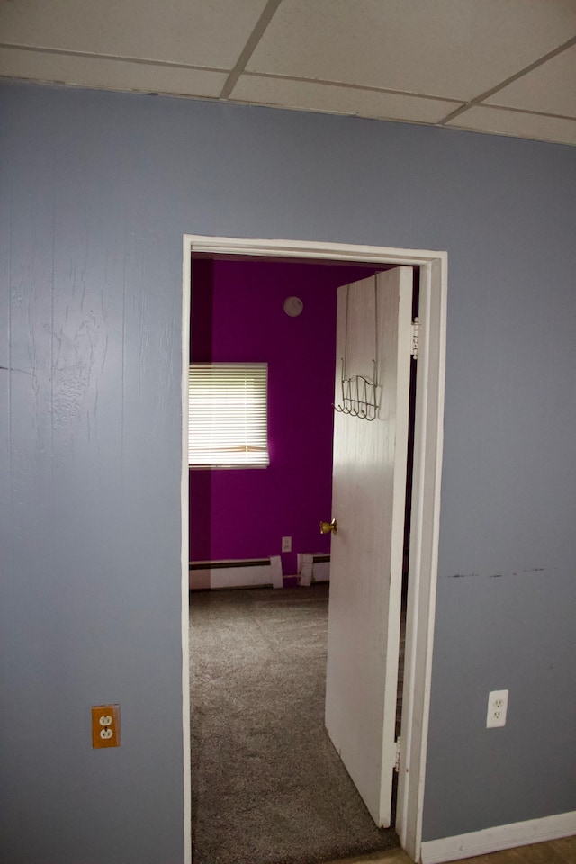 hallway with carpet, a paneled ceiling, and baseboard heating