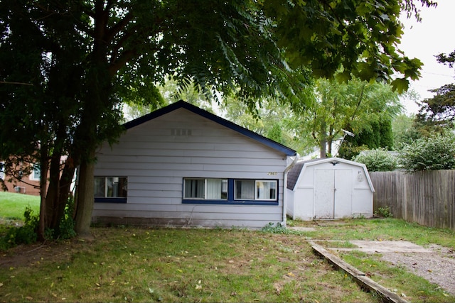 view of side of property featuring a storage unit and a lawn