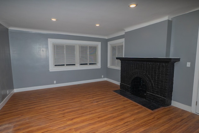 unfurnished living room with wood-type flooring and a brick fireplace