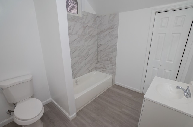 full bathroom featuring lofted ceiling, toilet, vanity, tiled shower / bath combo, and hardwood / wood-style flooring