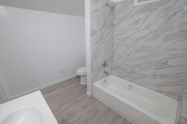 full bathroom with tiled shower / bath, toilet, sink, and hardwood / wood-style floors