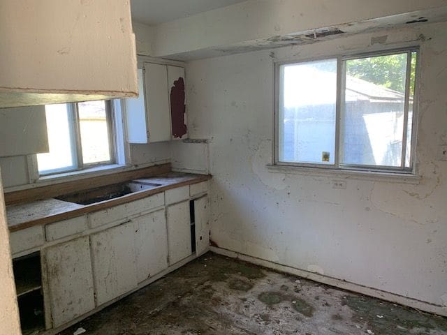 kitchen with a wealth of natural light, white cabinets, and black cooktop