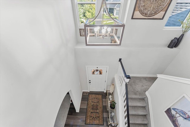 staircase featuring hardwood / wood-style flooring and an inviting chandelier