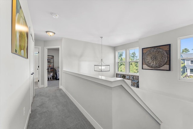 hall featuring carpet flooring and an inviting chandelier