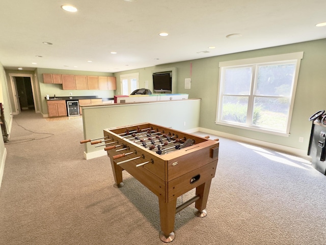 recreation room with plenty of natural light, light colored carpet, and beverage cooler