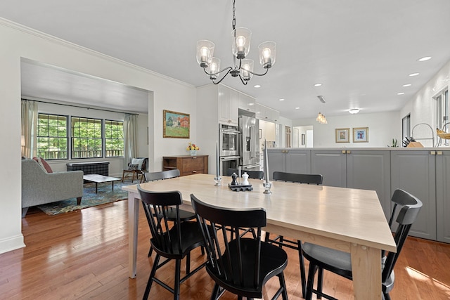 dining space featuring light wood-type flooring, an inviting chandelier, and crown molding