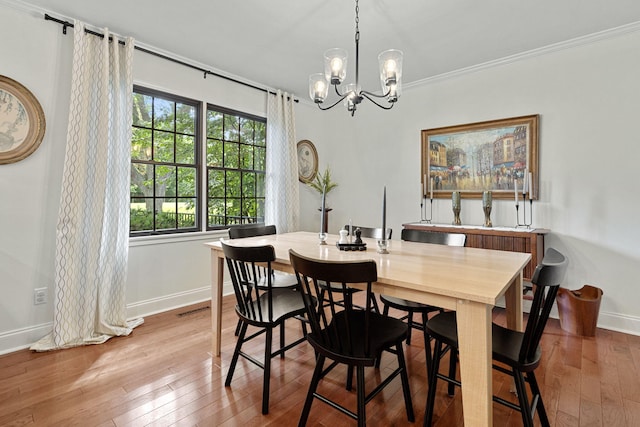 dining space featuring light wood-type flooring, an inviting chandelier, and crown molding