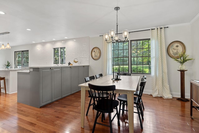 dining area with ornamental molding, a healthy amount of sunlight, a notable chandelier, and wood-type flooring