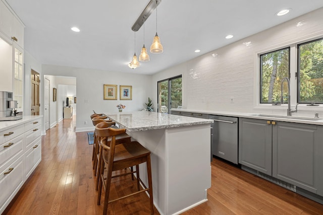 kitchen featuring sink, stainless steel dishwasher, pendant lighting, gray cabinets, and white cabinets