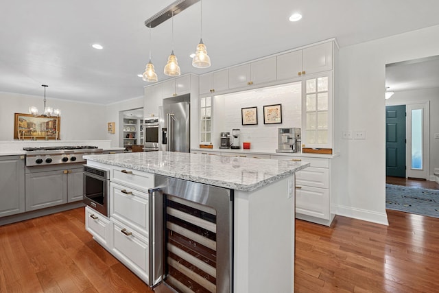 kitchen featuring light wood-type flooring, white cabinetry, stainless steel appliances, and beverage cooler