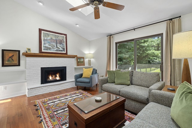 living room with ceiling fan, a fireplace, vaulted ceiling, and hardwood / wood-style flooring