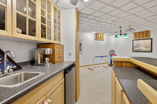 bar featuring light brown cabinetry, dishwasher, sink, and light carpet