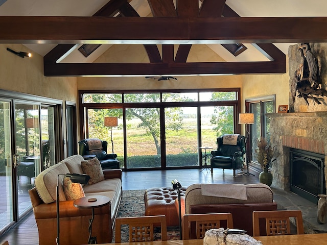 living room with beam ceiling, a stone fireplace, and high vaulted ceiling