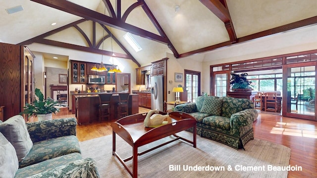 living room with high vaulted ceiling, beam ceiling, and light hardwood / wood-style floors