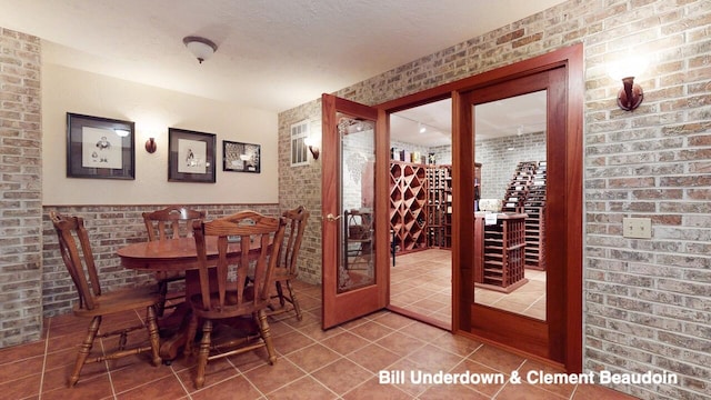 tiled dining area with brick wall and a textured ceiling