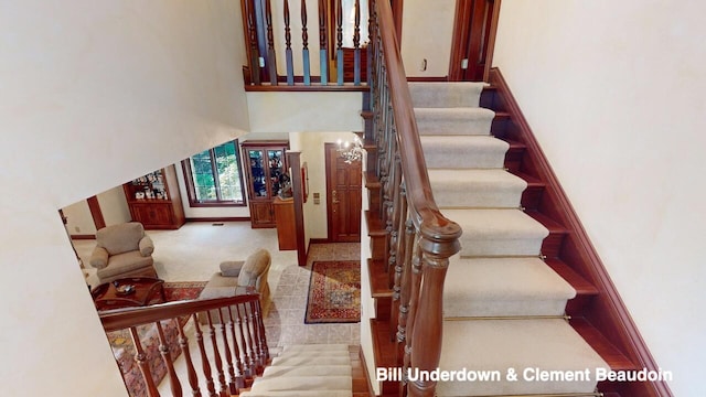 staircase with carpet floors and a towering ceiling