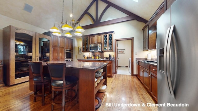 kitchen with appliances with stainless steel finishes, a center island, an inviting chandelier, and light hardwood / wood-style flooring