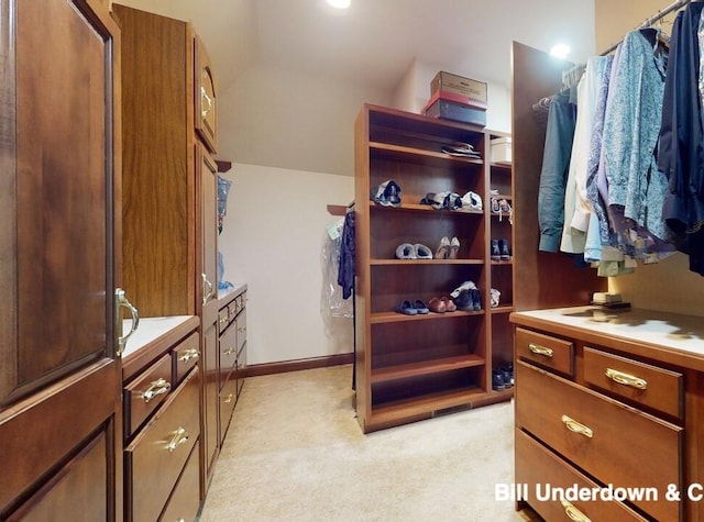 spacious closet with lofted ceiling and light carpet