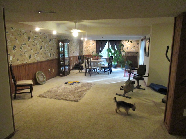 interior space featuring carpet floors, ceiling fan, and wooden walls