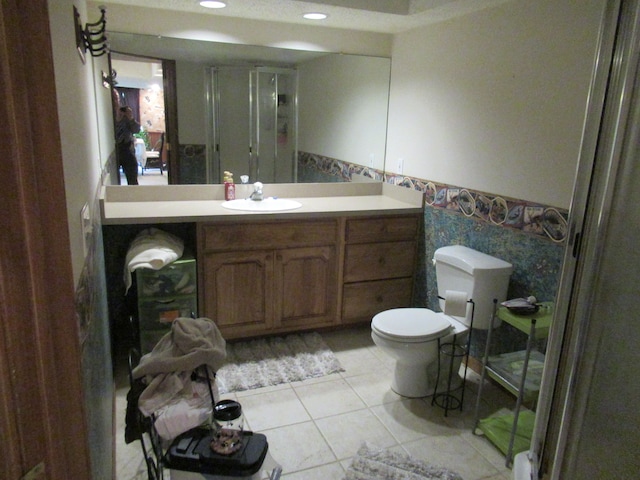 bathroom with vanity, a shower with door, tile walls, tile patterned flooring, and toilet