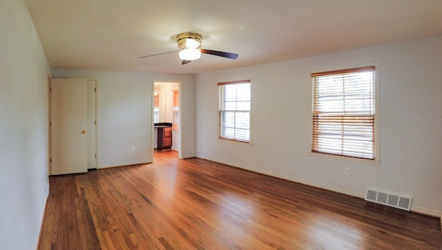 interior space featuring dark hardwood / wood-style flooring, ensuite bathroom, multiple windows, and ceiling fan