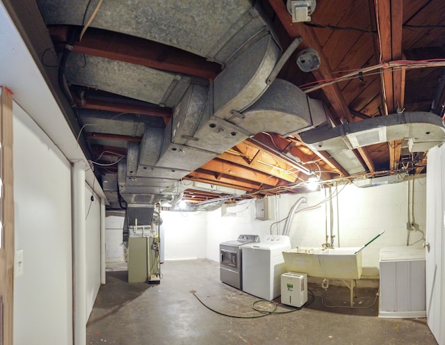 basement with washing machine and dryer, heating unit, and sink