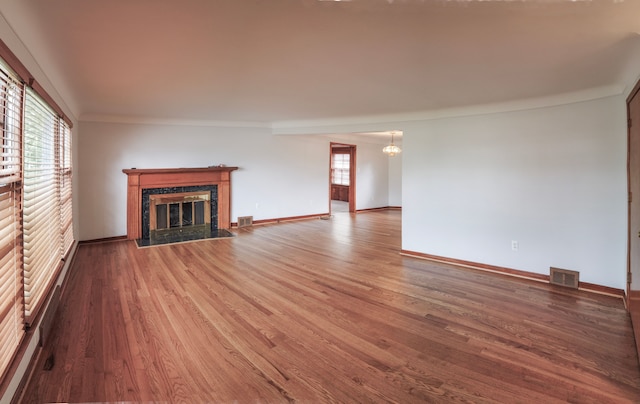 unfurnished living room featuring hardwood / wood-style flooring, a wealth of natural light, ornamental molding, and a premium fireplace