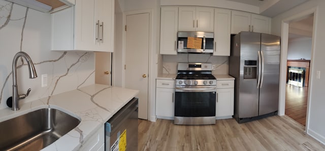 kitchen featuring white cabinetry, sink, tasteful backsplash, light hardwood / wood-style flooring, and appliances with stainless steel finishes