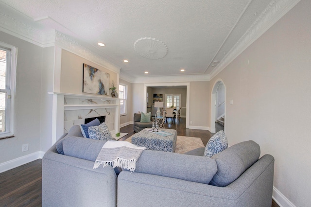 living room featuring crown molding, dark hardwood / wood-style flooring, a premium fireplace, and a textured ceiling