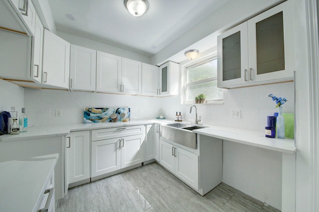 kitchen with backsplash, light stone countertops, sink, and white cabinets