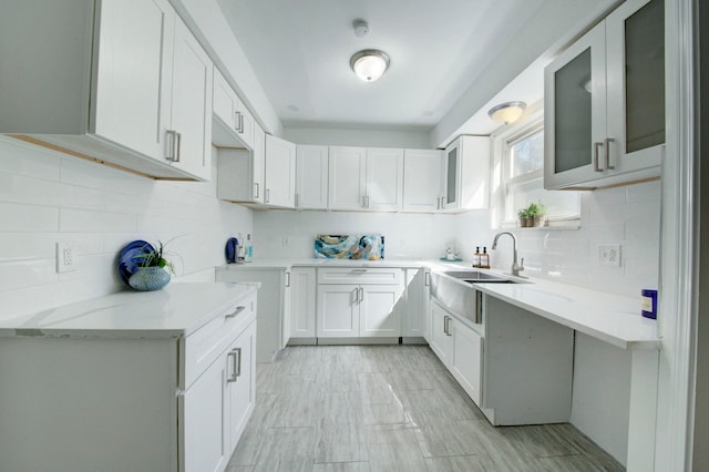 kitchen featuring white cabinetry, sink, light stone counters, and decorative backsplash