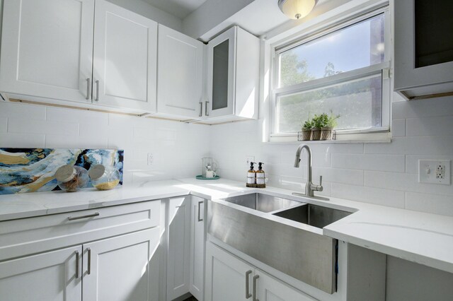 17566 Monica St, Detroit, MI 48221 - kitchen featuring backsplash, glass insert cabinets, light stone counters, white cabinets, and a sink