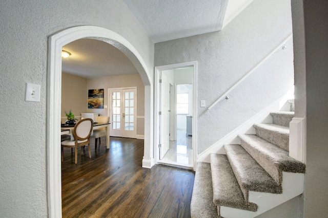 foyer entrance with dark wood-type flooring, a textured ceiling, and french doors