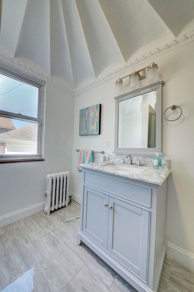 bathroom with vanity, radiator, and vaulted ceiling