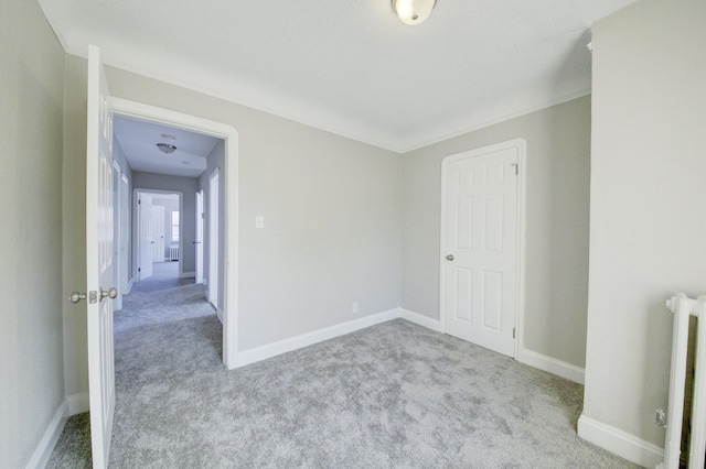 empty room featuring light carpet and radiator heating unit