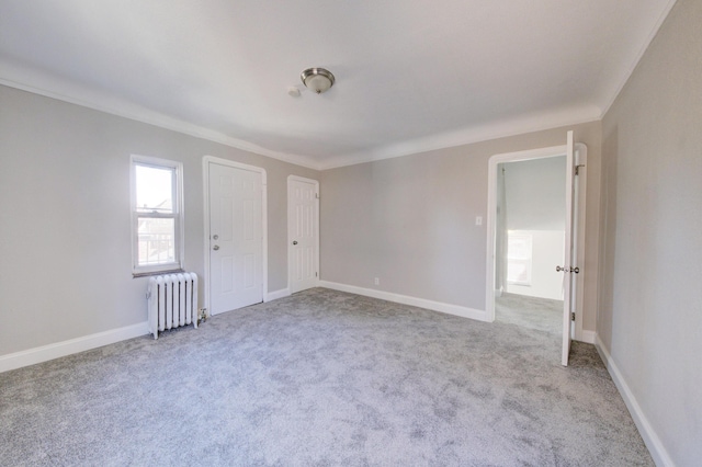 empty room featuring light colored carpet, radiator heating unit, and ornamental molding