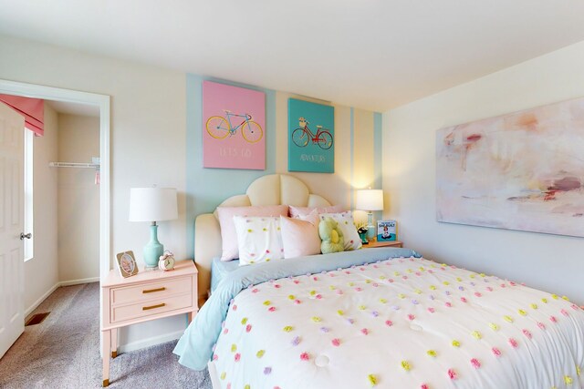 bedroom with a spacious closet, visible vents, baseboards, carpet flooring, and a closet