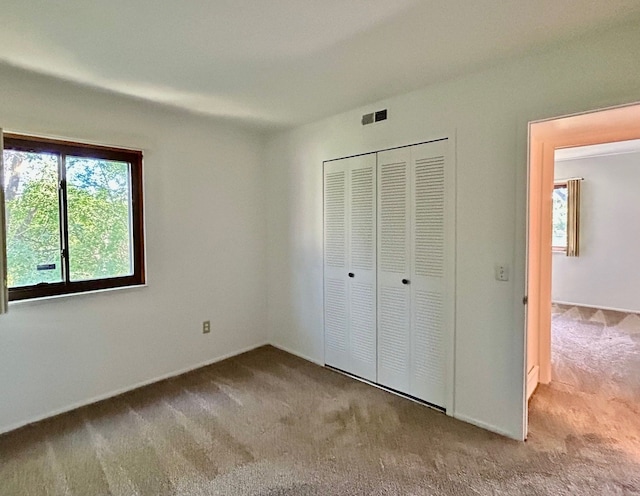 unfurnished bedroom featuring light carpet and a closet