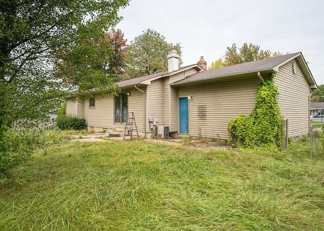 back of house featuring central air condition unit and a yard