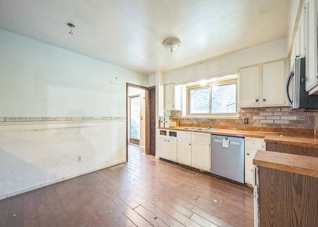 kitchen with hardwood / wood-style flooring, decorative backsplash, white cabinets, and stainless steel appliances