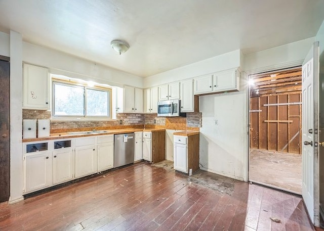 kitchen featuring appliances with stainless steel finishes, dark hardwood / wood-style flooring, backsplash, sink, and white cabinetry