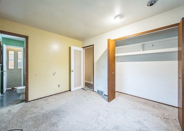 unfurnished bedroom featuring connected bathroom and light colored carpet