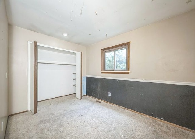 unfurnished bedroom featuring a closet and light colored carpet