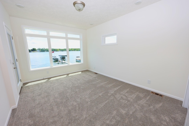 spare room featuring a water view and light colored carpet