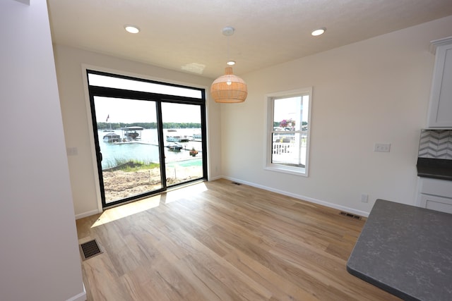 unfurnished dining area featuring a water view and light hardwood / wood-style floors