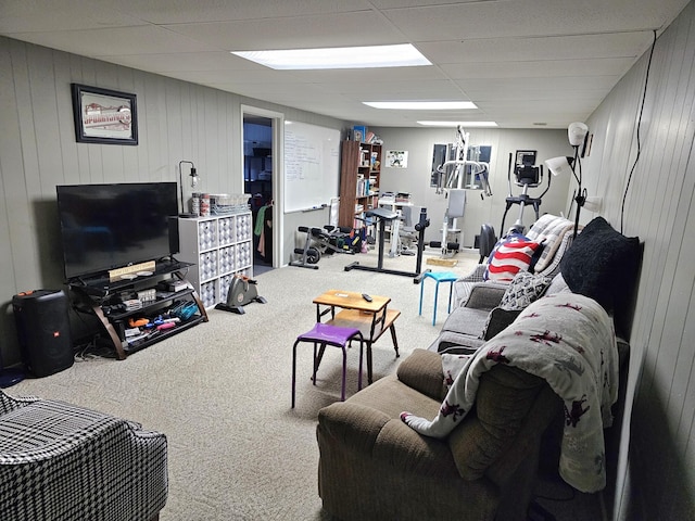 living room featuring a drop ceiling, carpet floors, and wooden walls