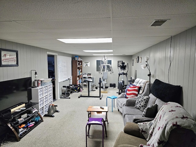 living room with wood walls, a drop ceiling, and carpet floors